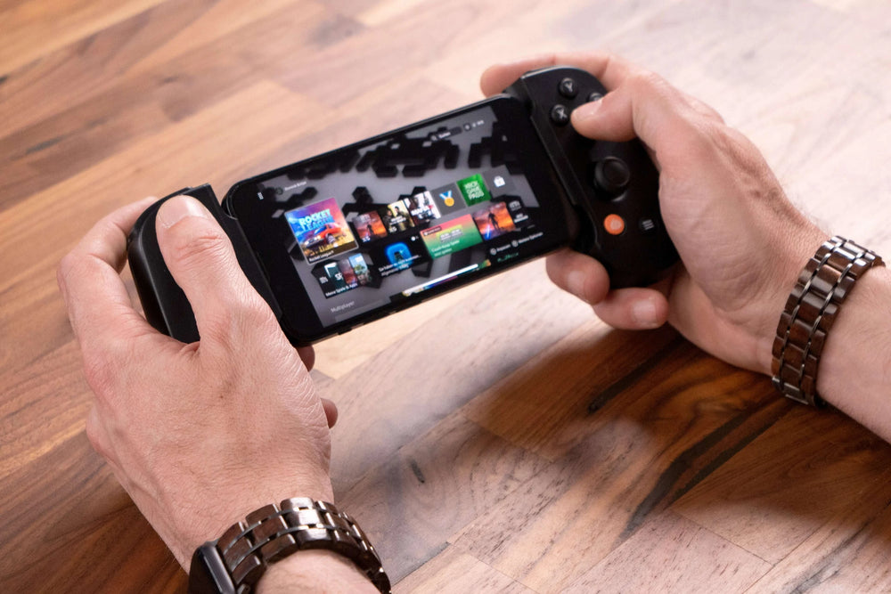 Ein Gamer hält einen tragbaren Controller mit einem Bildschirm, auf dem Spiele angezeigt werden, auf einem Holztisch.