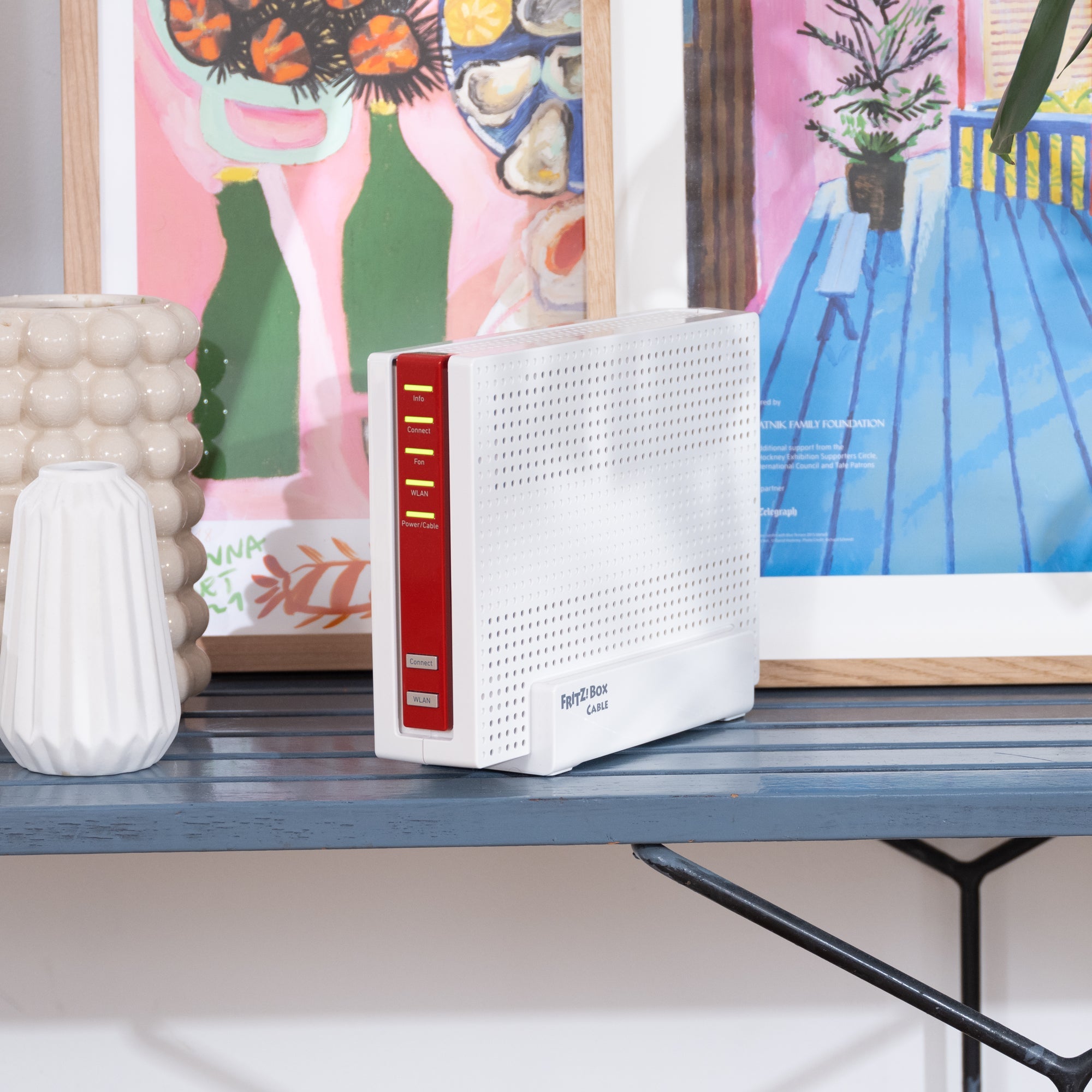 Moderne Fritz!Box auf einem Regal, umgeben von Dekoration und Kunstwerken, ideal für schnelles WLAN.