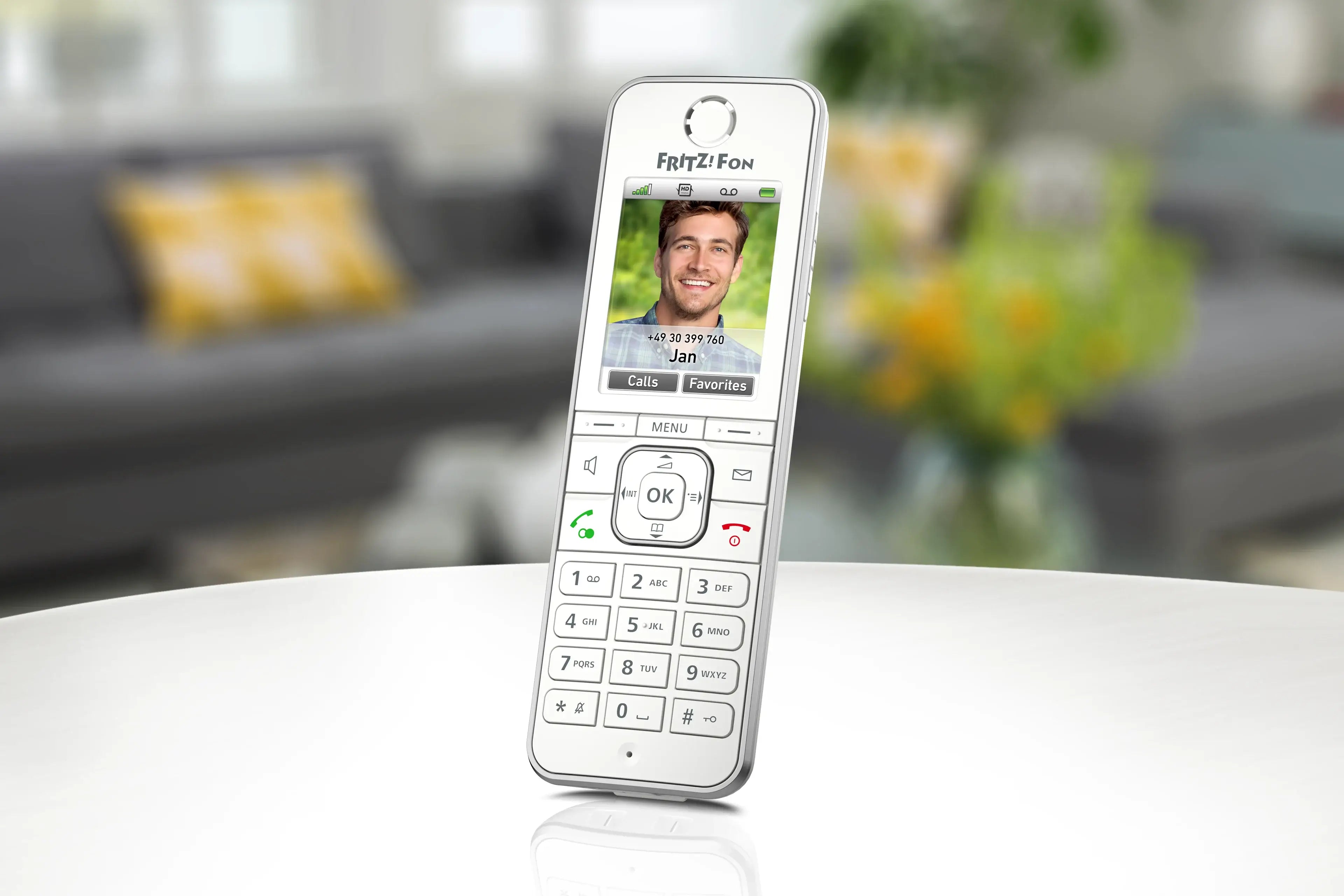 Fritz Fon Telefon mit Kontaktbild und Tasten, auf einem Tisch in freundlicher Wohnumgebung.