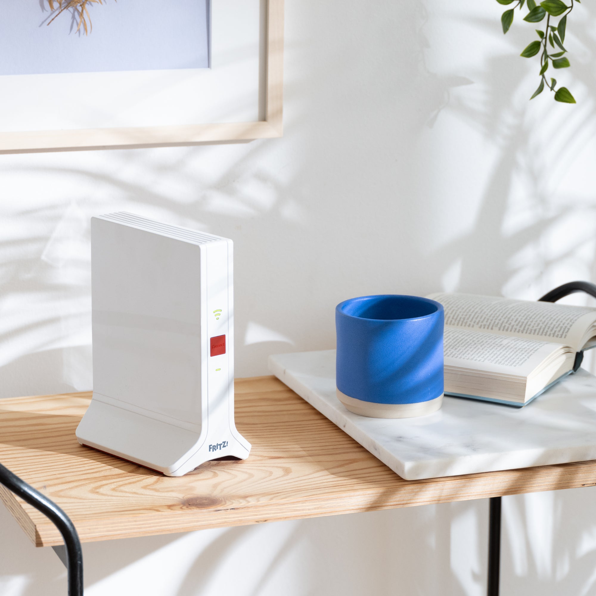 FRITZ!Repeater 3000 AX auf einem modernen Tisch mit Pflanzen und einer blauen Tasse.