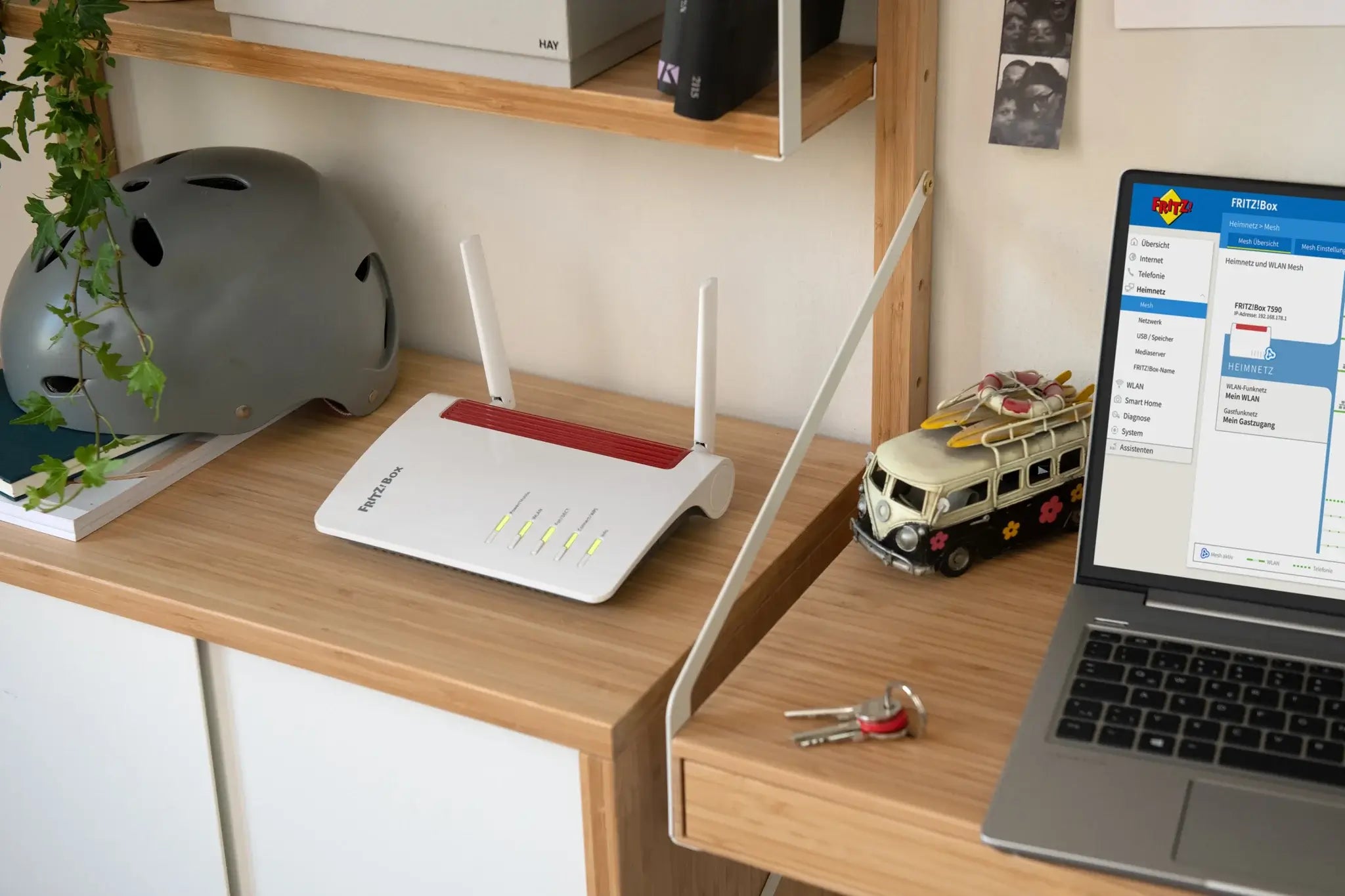 FRITZ!Box 6850 5G Router auf einem Holztisch mit Laptop, Schlüssel und Stratospider-Koffer, grauem Helm im Hintergrund.