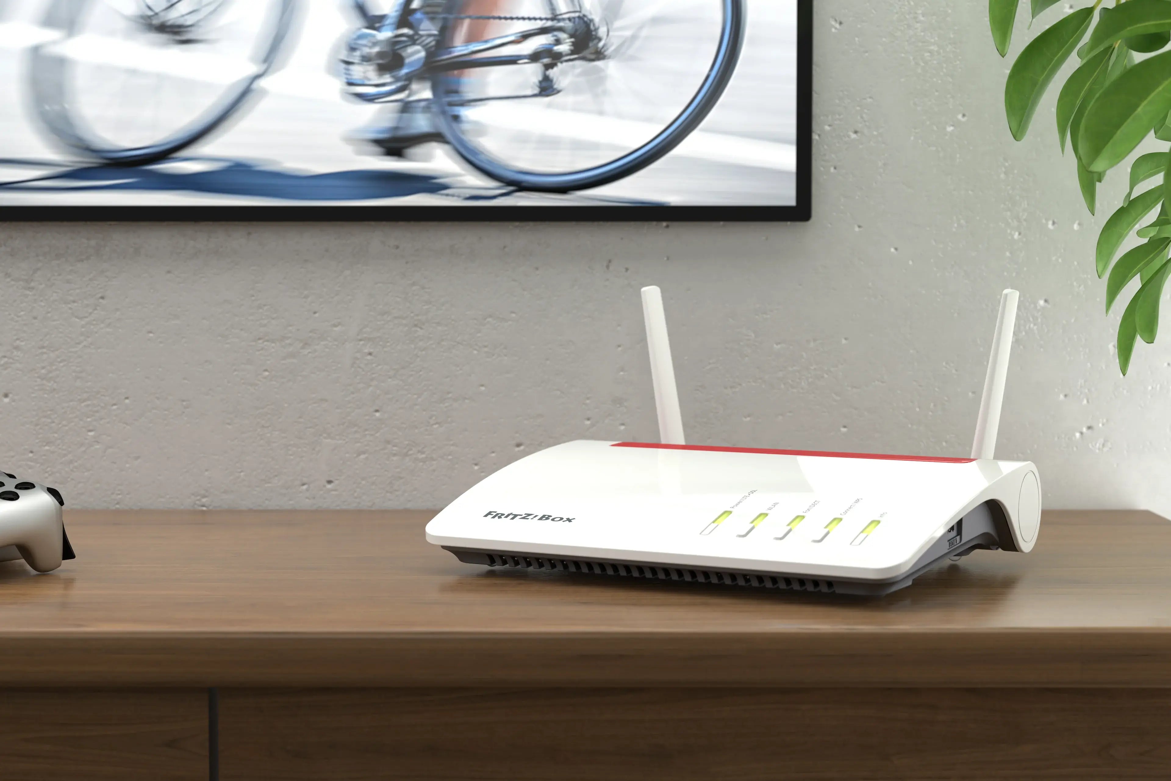 Moderne WLAN-Router auf Tisch mit Spielkonsole, Hintergrundbild von Radfahrern, stilvolle Einrichtung